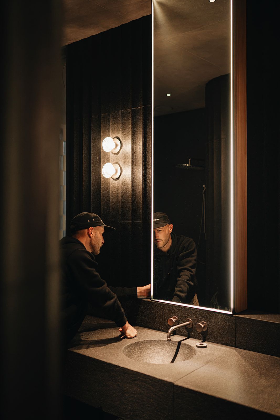 Dark luxury bathroom with backlit mirror and stone basin