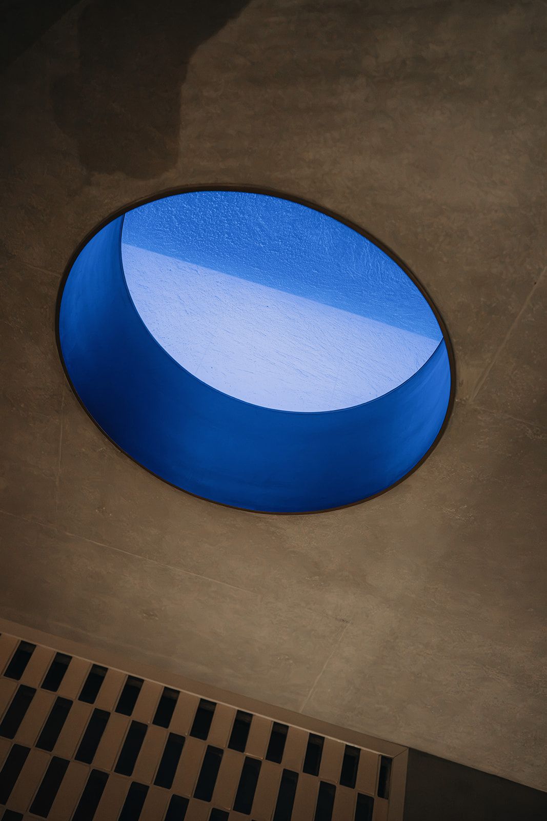 Blue circular skylight void set into a polished concrete ceiling